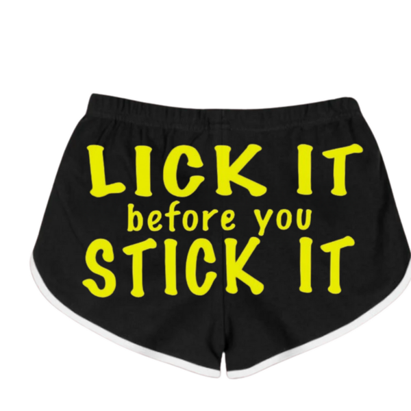 Bold, eye-catching women's black and neon yellow booty shorts with the text "LICK IT BEFORE YOU STICK IT" displayed prominently in the center.